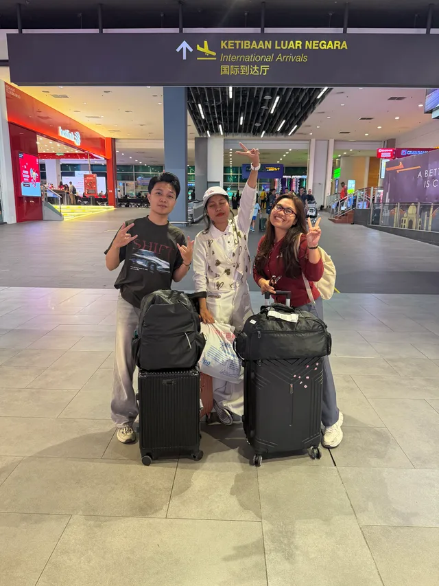 Three students standing with luggage in the airport arrivals hall